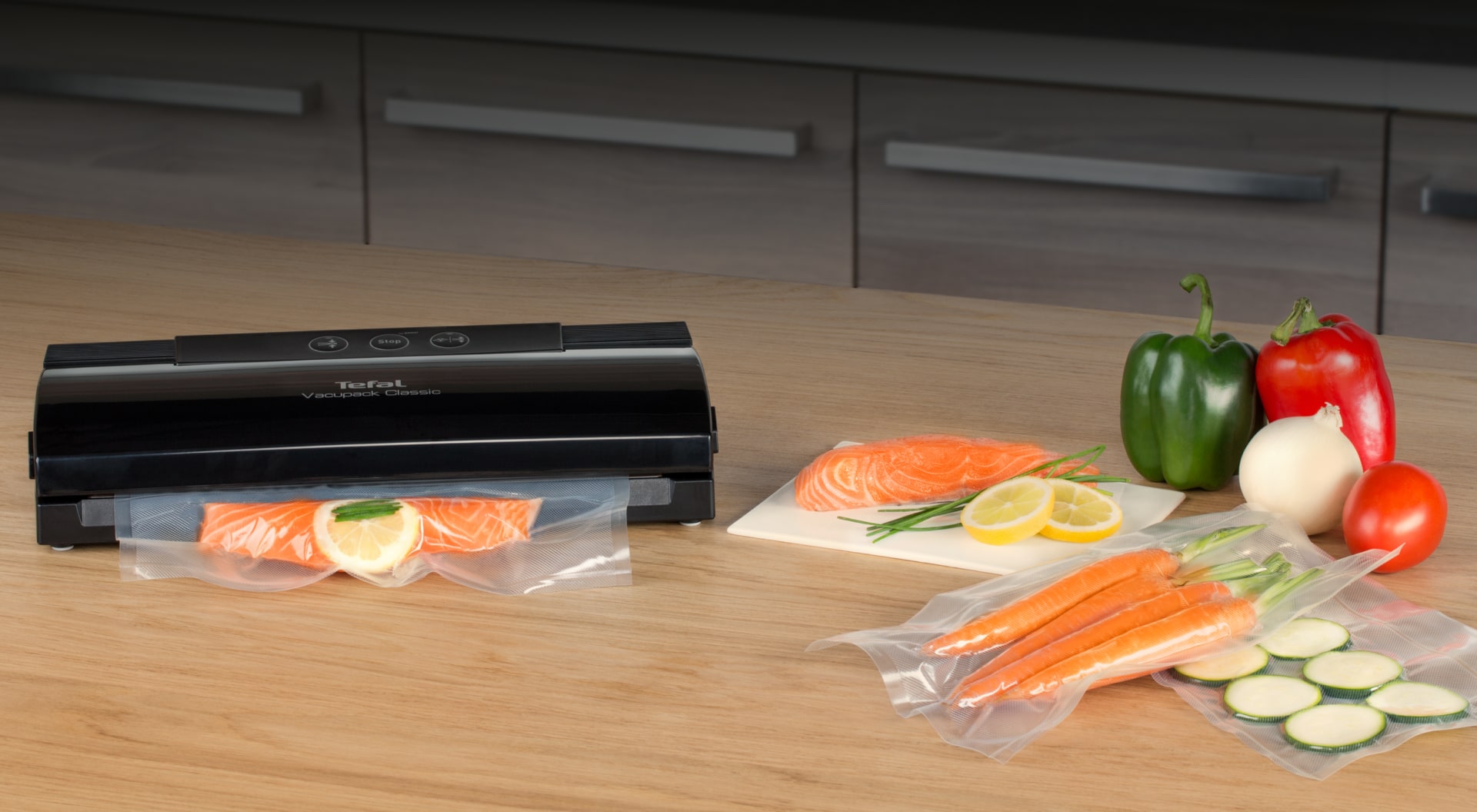 Вакуумний пакувальник Tefal Classic на столі із запакованими та свіжими продуктами харчування.